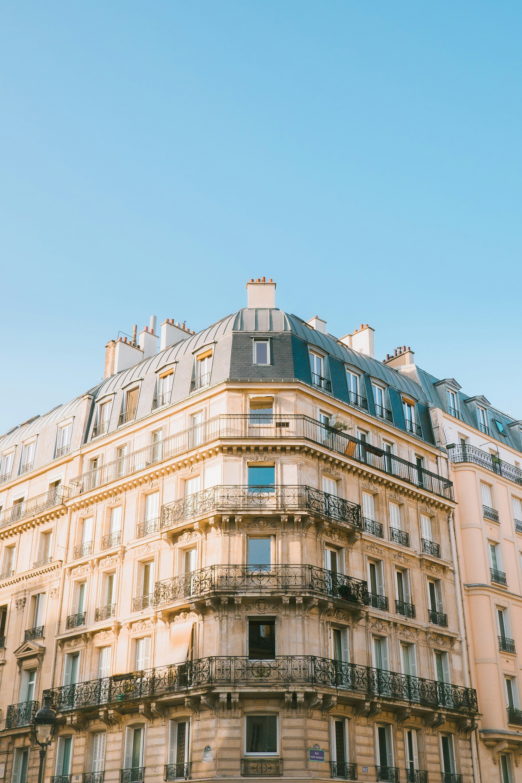 Immeuble haussmannien d'angle à Paris, façade en pierre de taille et balcons en fer forgé