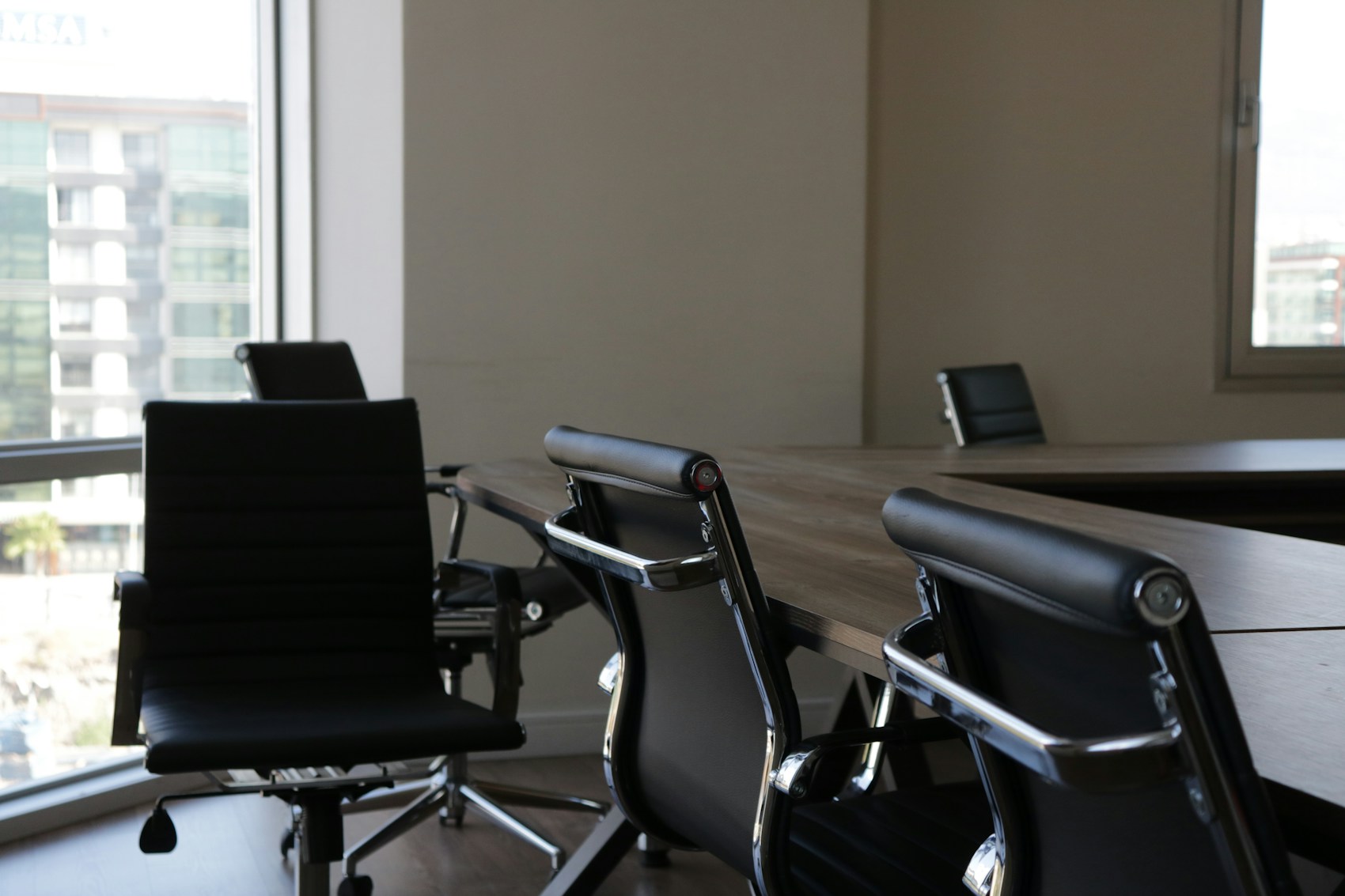 Salle de réunion du cabinet, table et fauteuils devant une baie vitrée